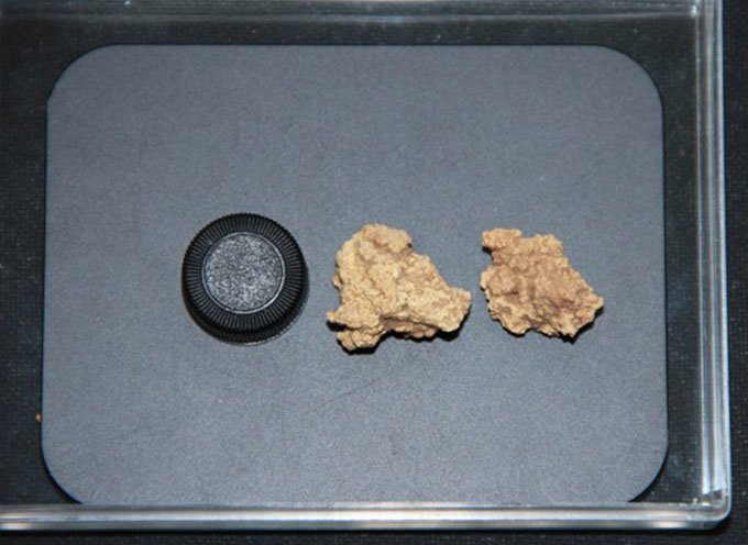 Two ancient cheese curds on a plate next to a bottle cap, which is roughly the same size.