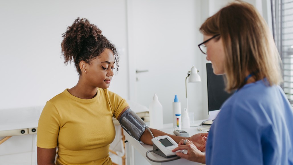 A person has their blood pressure taken while seated with their arm supported on a table and at heart height