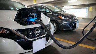 A white Nissan electric car with a charger stuck into the front